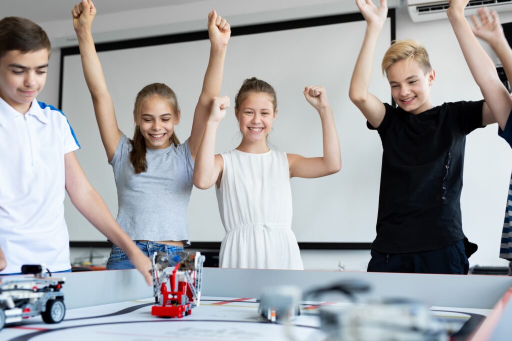 Children in robotics classes celebrate victory in robot battles.