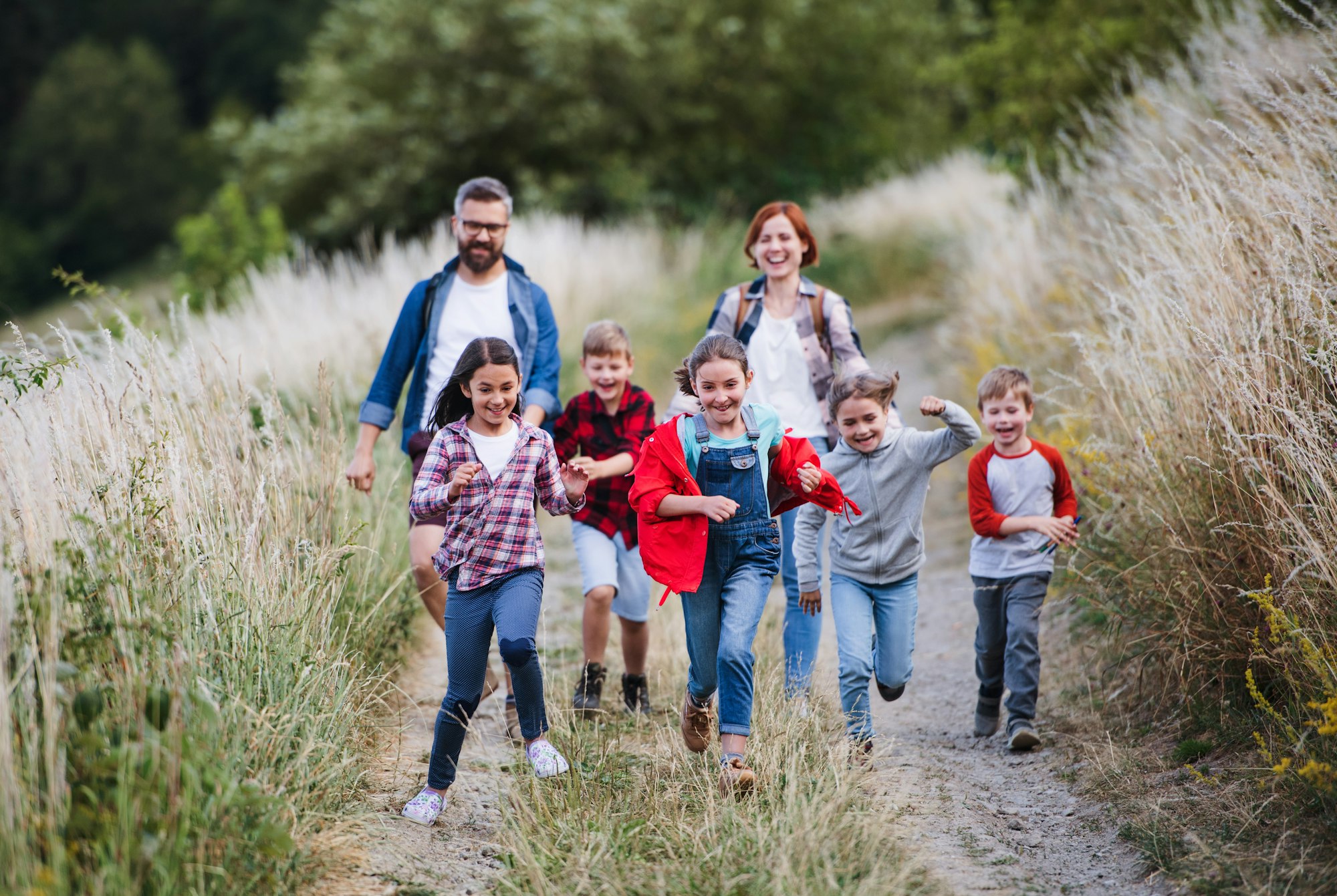Group of school children with teacher on field trip in nature, running