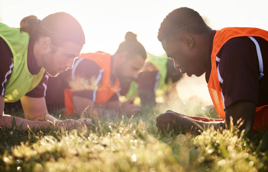 Sports, team and soccer group plank on field for fitness training, workout or exercise core outdoor