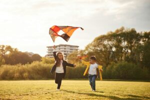 Two kids are playing with kite on the summer field